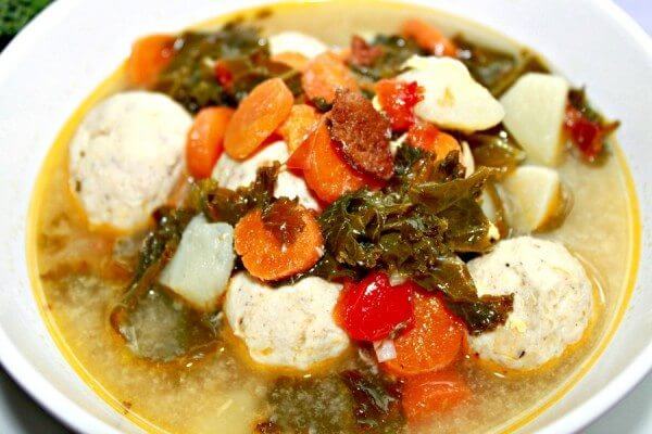 Creamy chicken soup with kale and bacon on a white plate