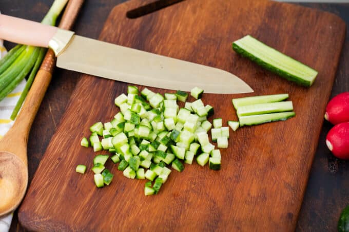 Chopping cucumbers on a cutting board.