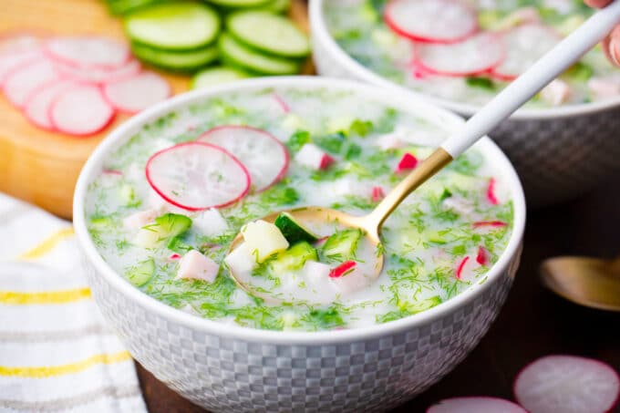 A bowl of cold summer soup Russian okroshka made with fresh veggies.