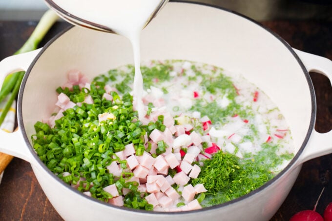Pouring creamy broth into Russian Okroshka.