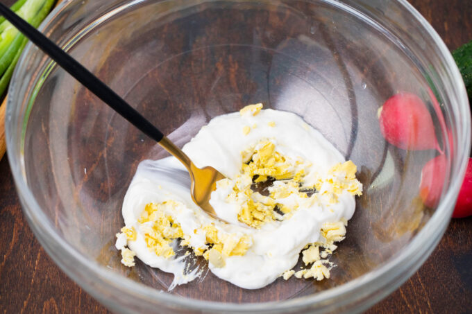 Stirring sour cream and egg yolk in a bowl.