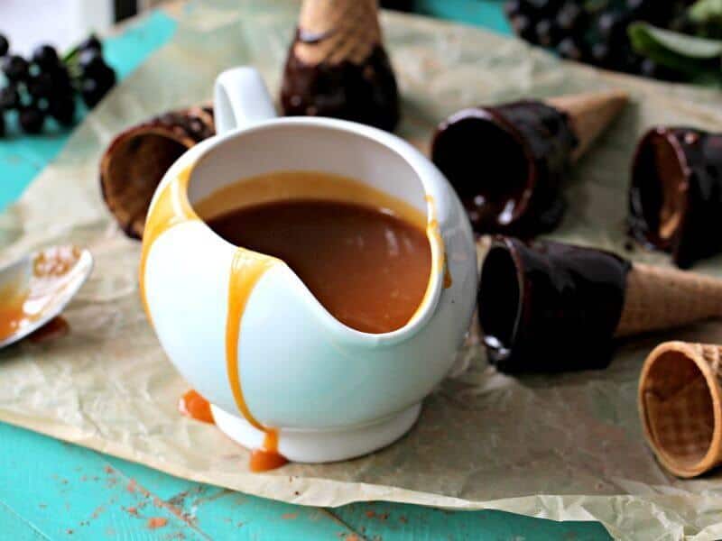 Caramel sauce in a saucer and ice cream cones in the background