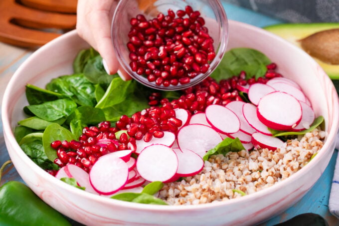 Making a salad with buckwheat, radishes, spinach, and pomegranate seeds.