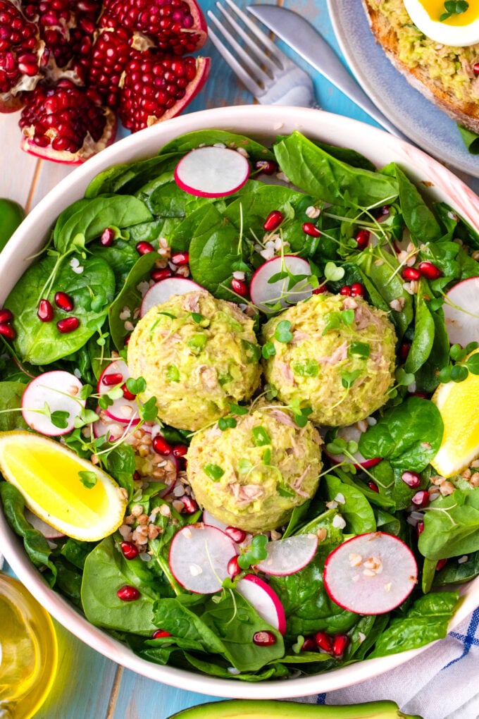 Overhead shot of spinach salad topped with mayo-free, creamy, avocado tuna salad.
