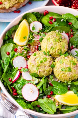 Spinach salad topped with mayo-free, creamy, avocado tuna salad with radishes.
