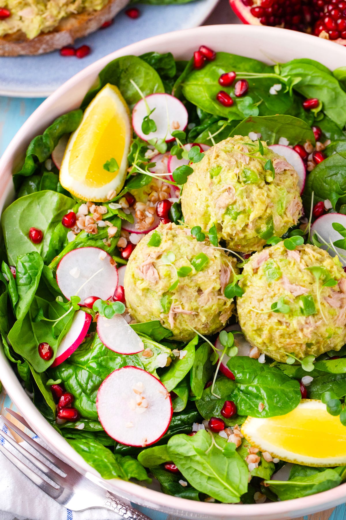 Spinach salad topped with mayo-free, creamy, avocado tuna salad with radishes.