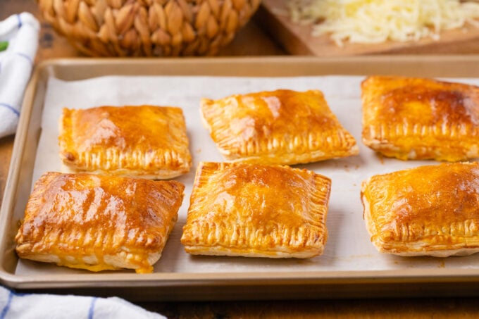 Puff pastry cheese pockets on a baking sheet.