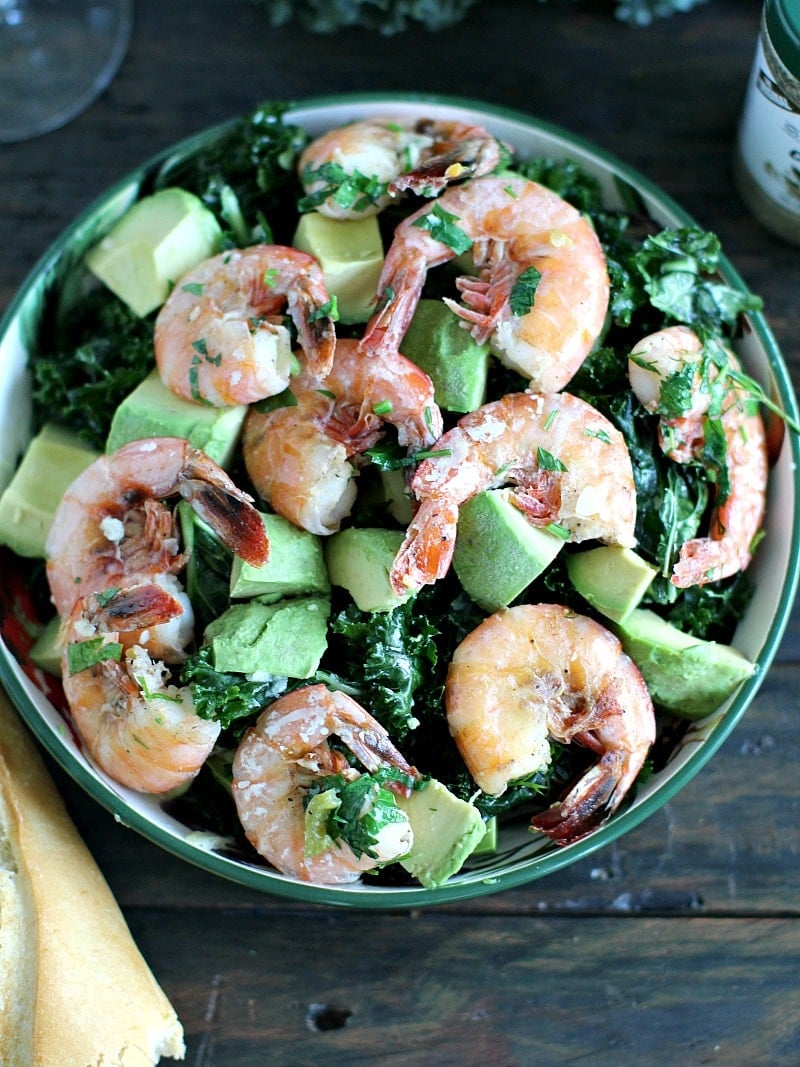 Garlic kale salad topped with garlicky shrimp cooked in sauvignon blanc and served with buttery avocado is the perfect summer meal.