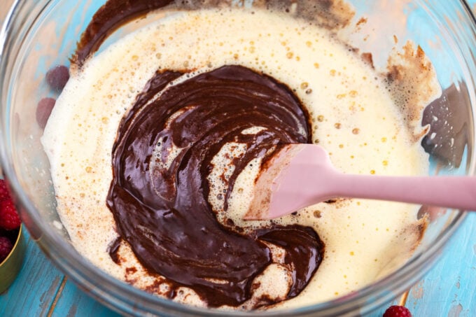 Combining beaten eggs and melted chocolate.