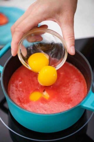 adding egg yolks to make strawberry curd