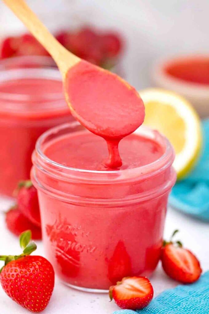 strawberry curd dripping of a spoon into a mason jar