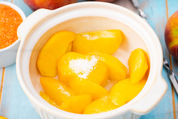 Peach slices in a baking dish with sugar.