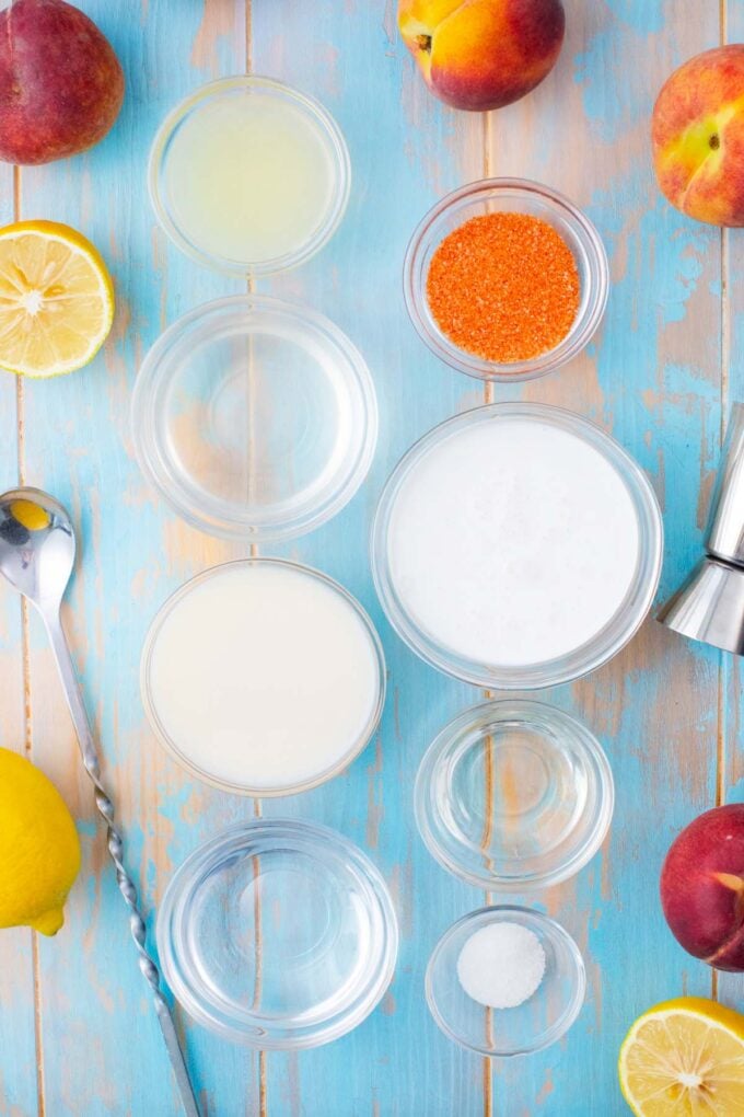Overhead shot of peaches and cream martini ingredients in bowls on a table.