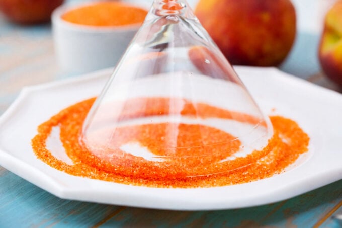 Dipping the rim of a martini glass in orange sanding sugar.