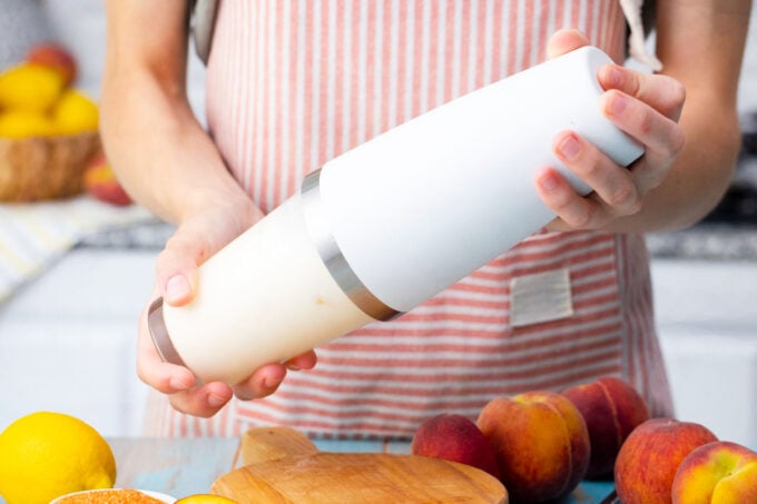 Shaking peaches and cream martini in a cocktail shaker.
