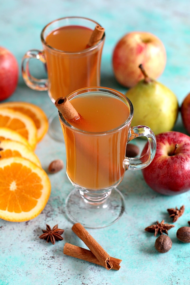 Apple cider garnished with star anise and whole cinnamon sticks in individual glass cups