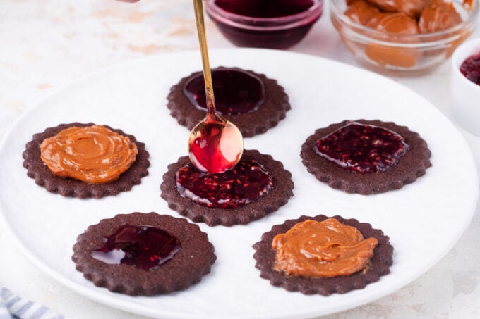 Filling chocolate Linzer cookies with Dulce de leche and raspberry jam.