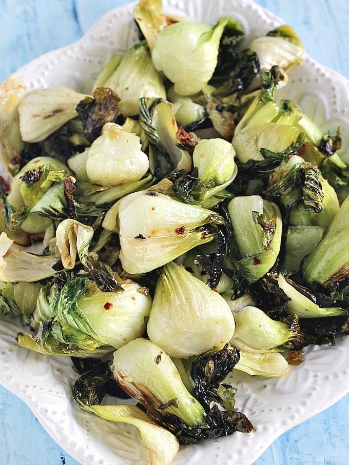 Image of cooked bok choy with garlic and sesame seeds on a white plate.