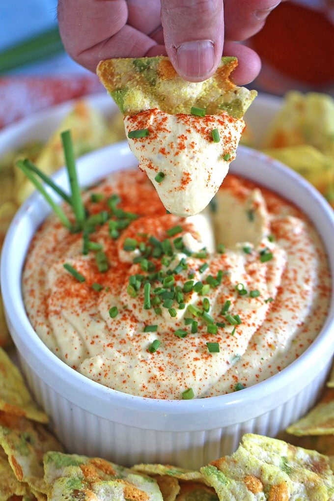 a veggie chip dipper in deviled eggs dip with chives.