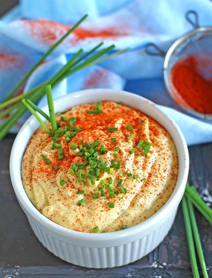 a bowl of homemade deviled eggs dip topped with paprika and chives