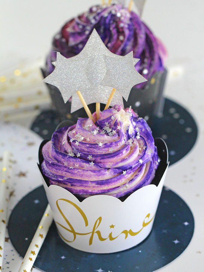 Galaxy Cupcakes topped with purple and white swirl frosting and shiny stars