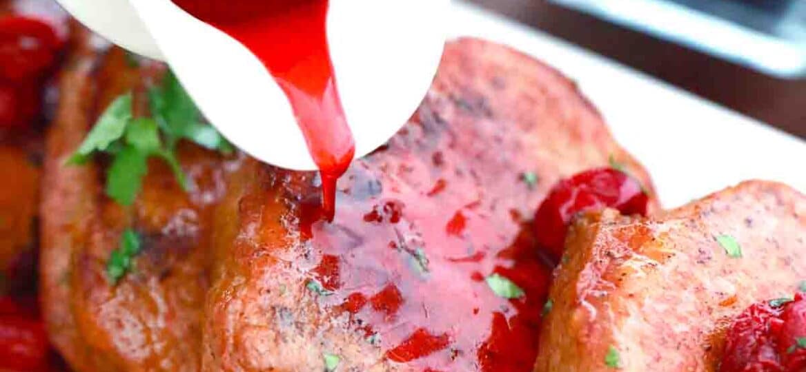 pouring cherry sauce over boneless pork chops