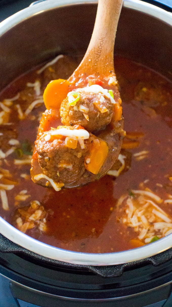 holding meatball in a wooden spoon over Instant Pot Italian Meatball Soup