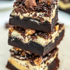 Slutty Cheesecake Brownie Bars made with a layer of fudgy brownie, Oreos, cheesecake, chocolate ganache and chopped Snickers bars. #