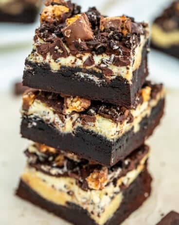 Slutty Cheesecake Brownie Bars made with a layer of fudgy brownie, Oreos, cheesecake, chocolate ganache and chopped Snickers bars. #