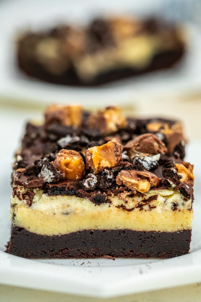 Photo of chocolate oreo brownies bars topped with chopped snickers.