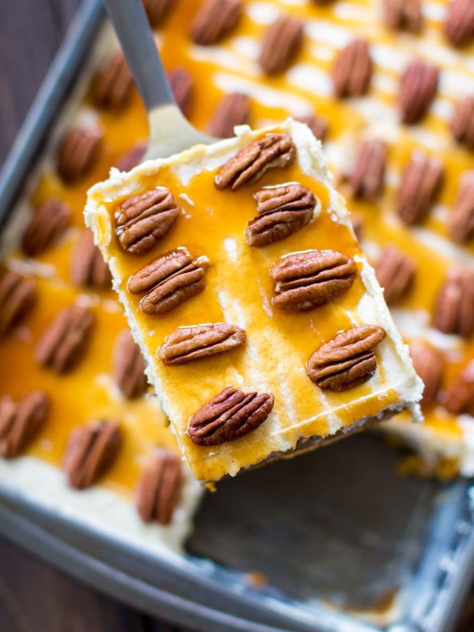 A slice of homemade pumpkin poke cake topped with pecans and caramel sauce