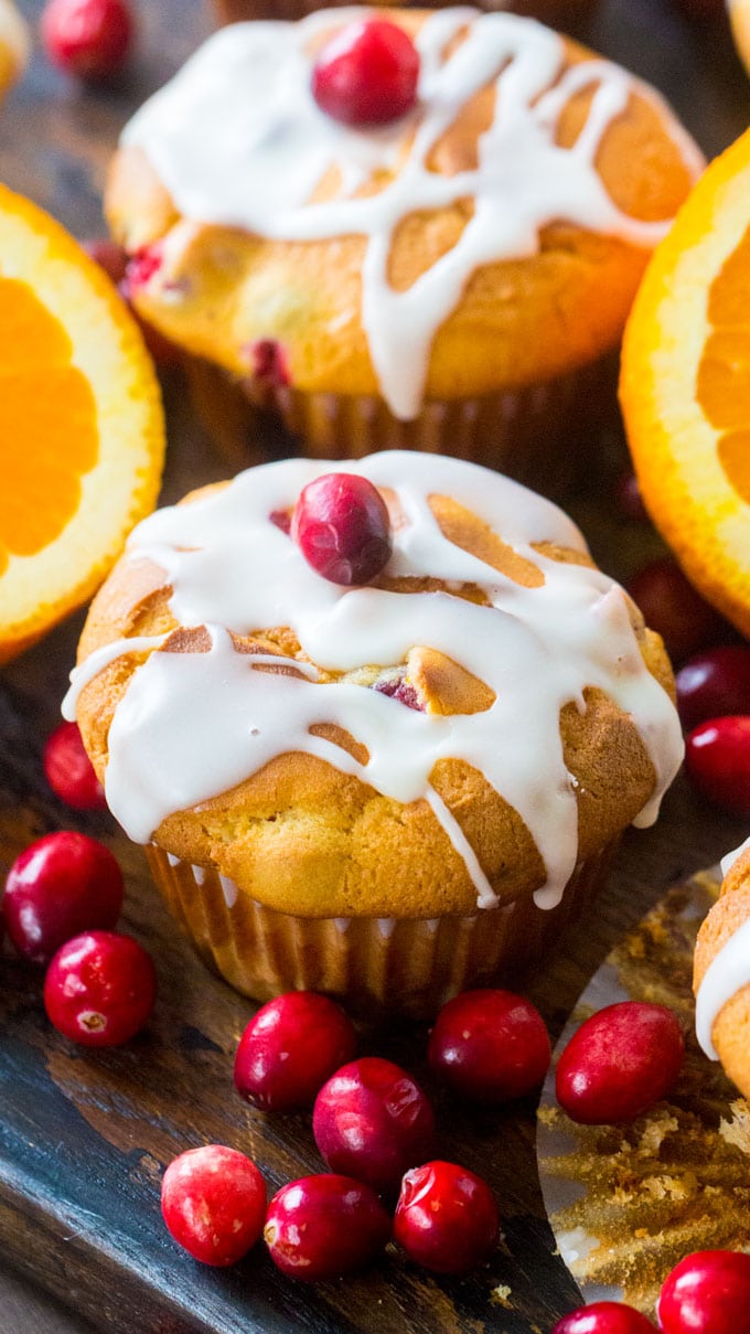 Cranberry Orange Muffins topped with a white glaze and fresh oranges next to them