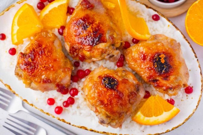 cranberry orange chicken served with fresh oranges on top of rice