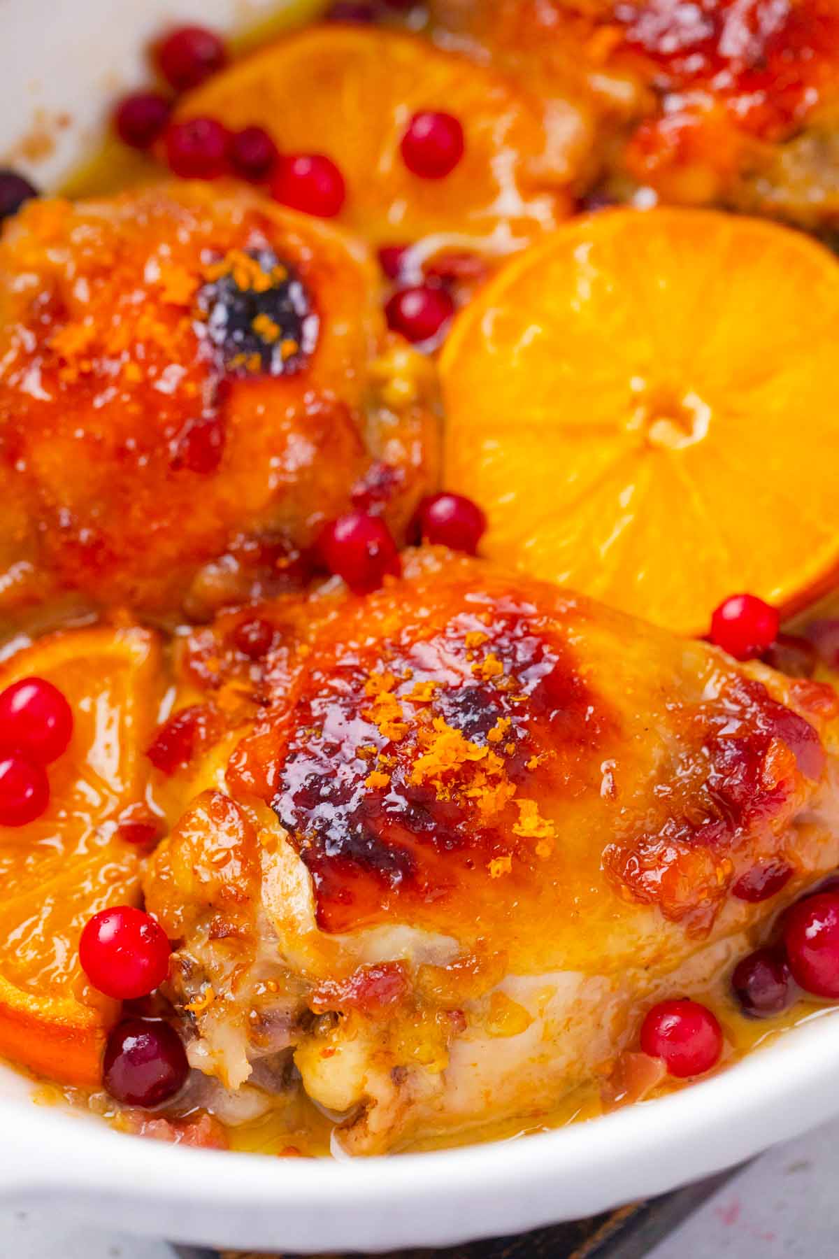 a pan of crispy oven baked cranberry orange chicken thighs with fresh oranges