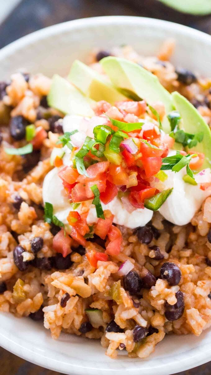 Image of slow cooker rice and beans garnished with sour cream and sliced avocado.