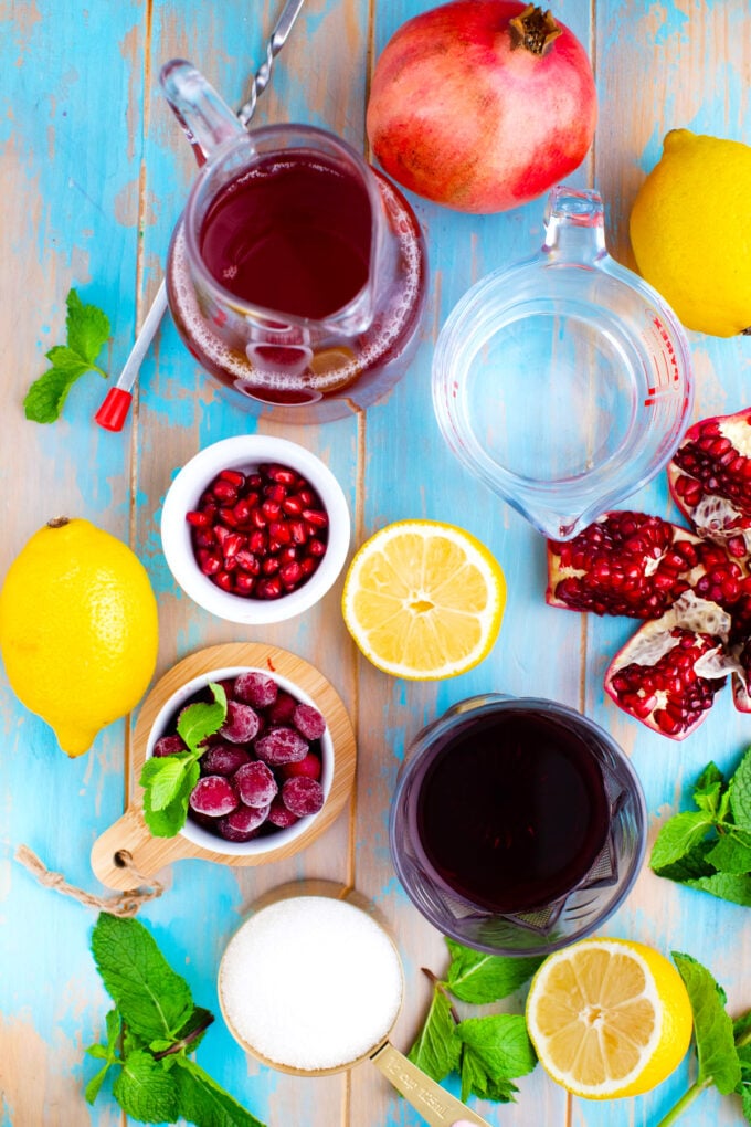 Overhead shot of cranberry mocktail ingredients on a blue table.