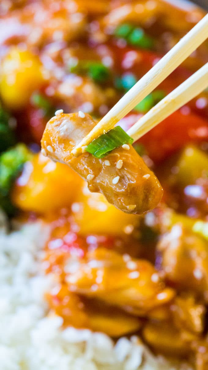 Holding with chopsticks a piece of Instant Pot Sweet and Sour Chicken.