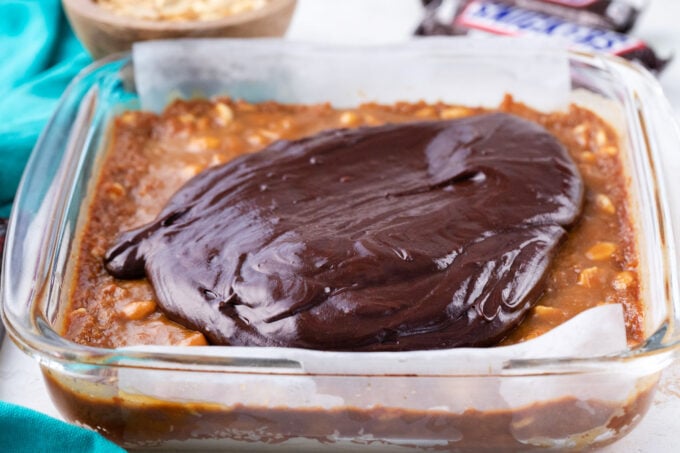 Adding chocolate ganache layer over Snickers cookie bars.