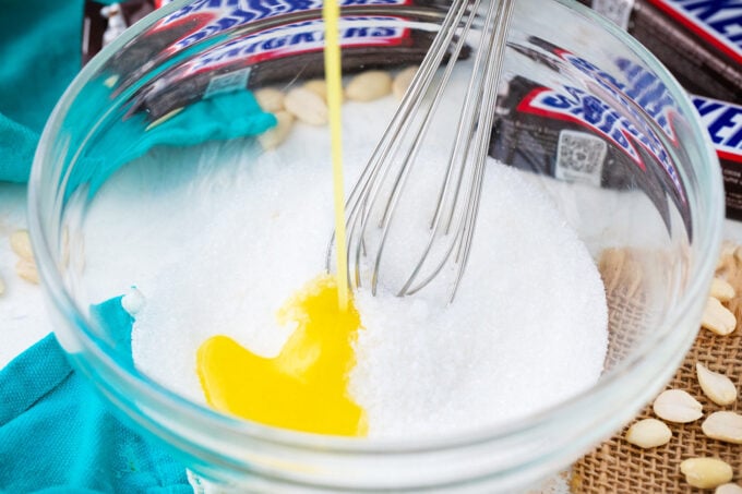 Pouring melted butter in a bowl of sugar.