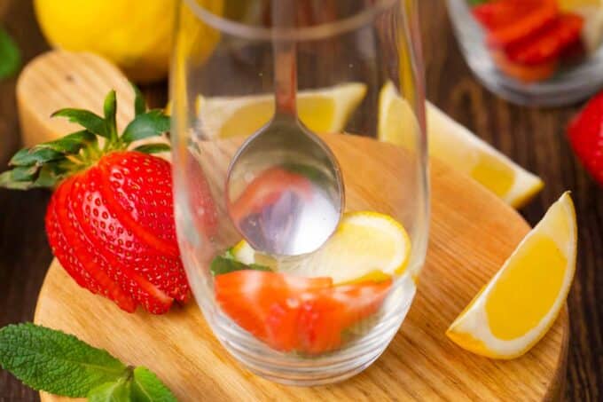 muddling strawberries and lemon in a glass