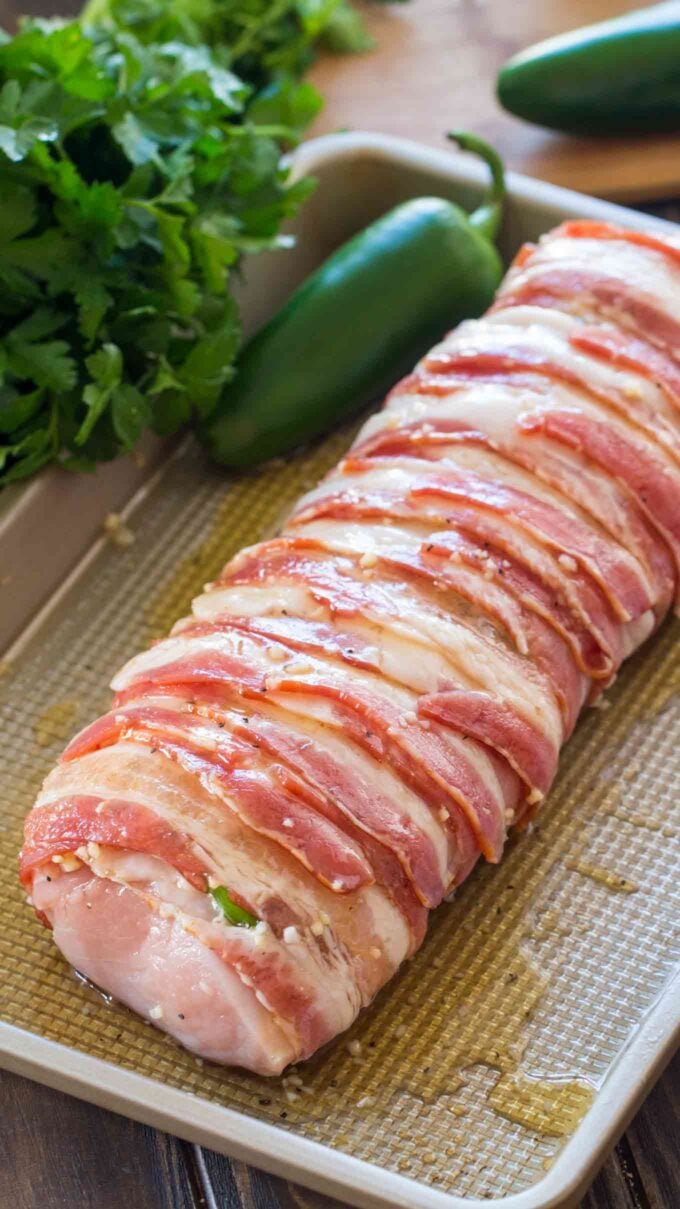 Image of pork tenderloin wrapped in bacon on a cooking tray.