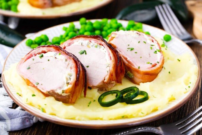 Bacon wrapped pork tenderloin with cream cheese over mashed potatoes.