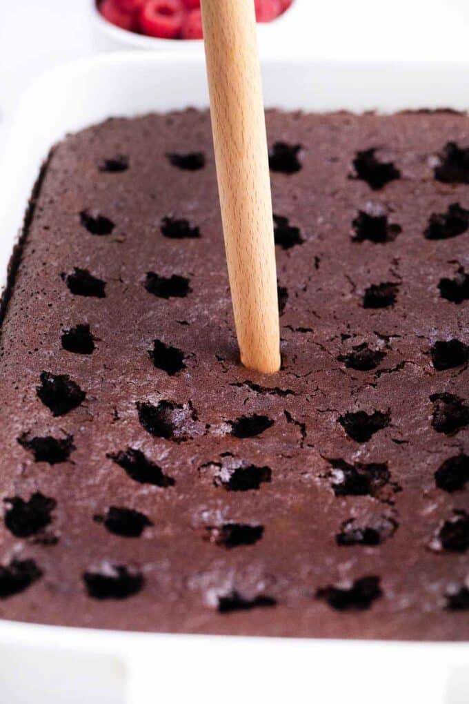 poking holes with a wooden spoon in a chocolate cake