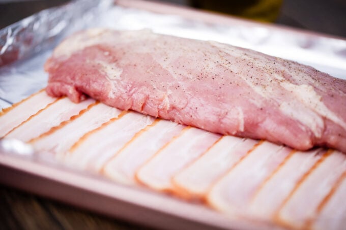 Pork tenderloin on top of bacon slices.