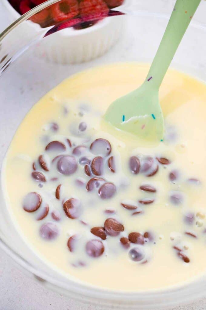 stirring condensed milk and chocolate chips in a bowl