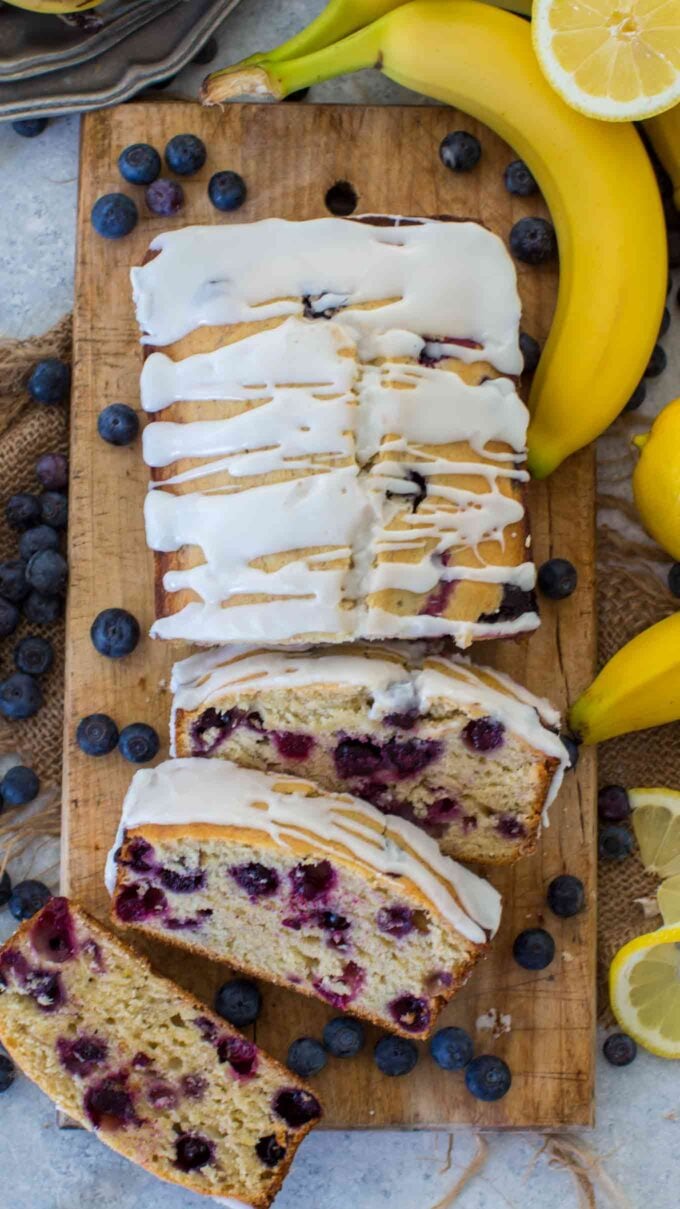 homemade. lemon blueberry banana bread topped with sugar glaze on a cutting board