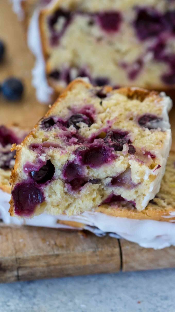 sliced blueberry banana bread with lots of juicy blueberries on a wooden board