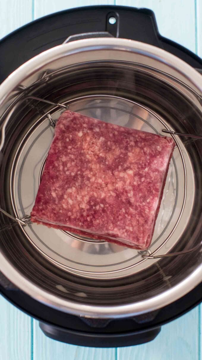 a block of frozen ground beef on a trivet in the instant pot