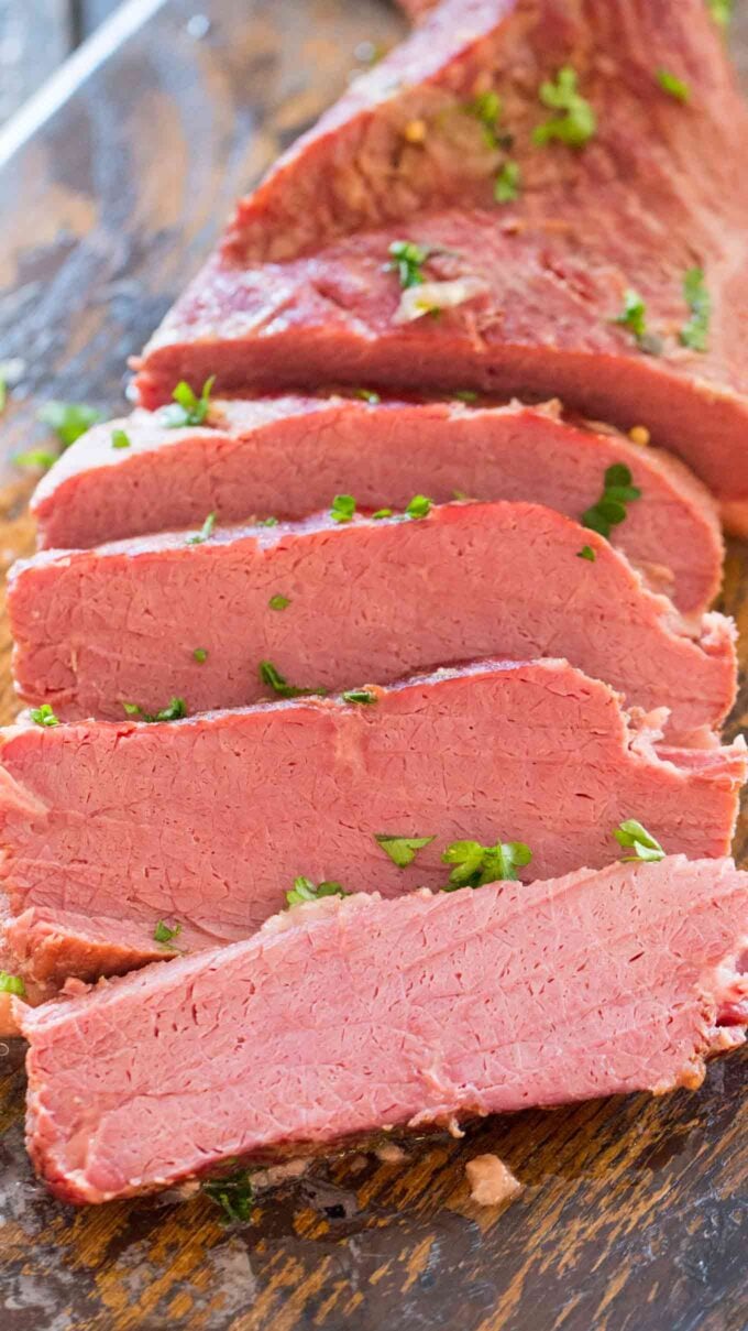 Sliced tender Instant Pot Corned Beef on a wooden board