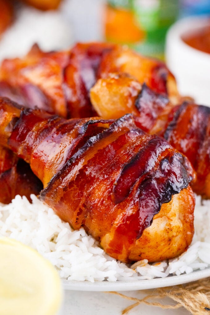 Bacon wrapped chicken drumsticks over rice.